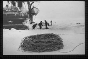 Image of KARLUK in ice, men working beside her. Large coil of line for Lucas sounding-machine near dredge-hole at stern